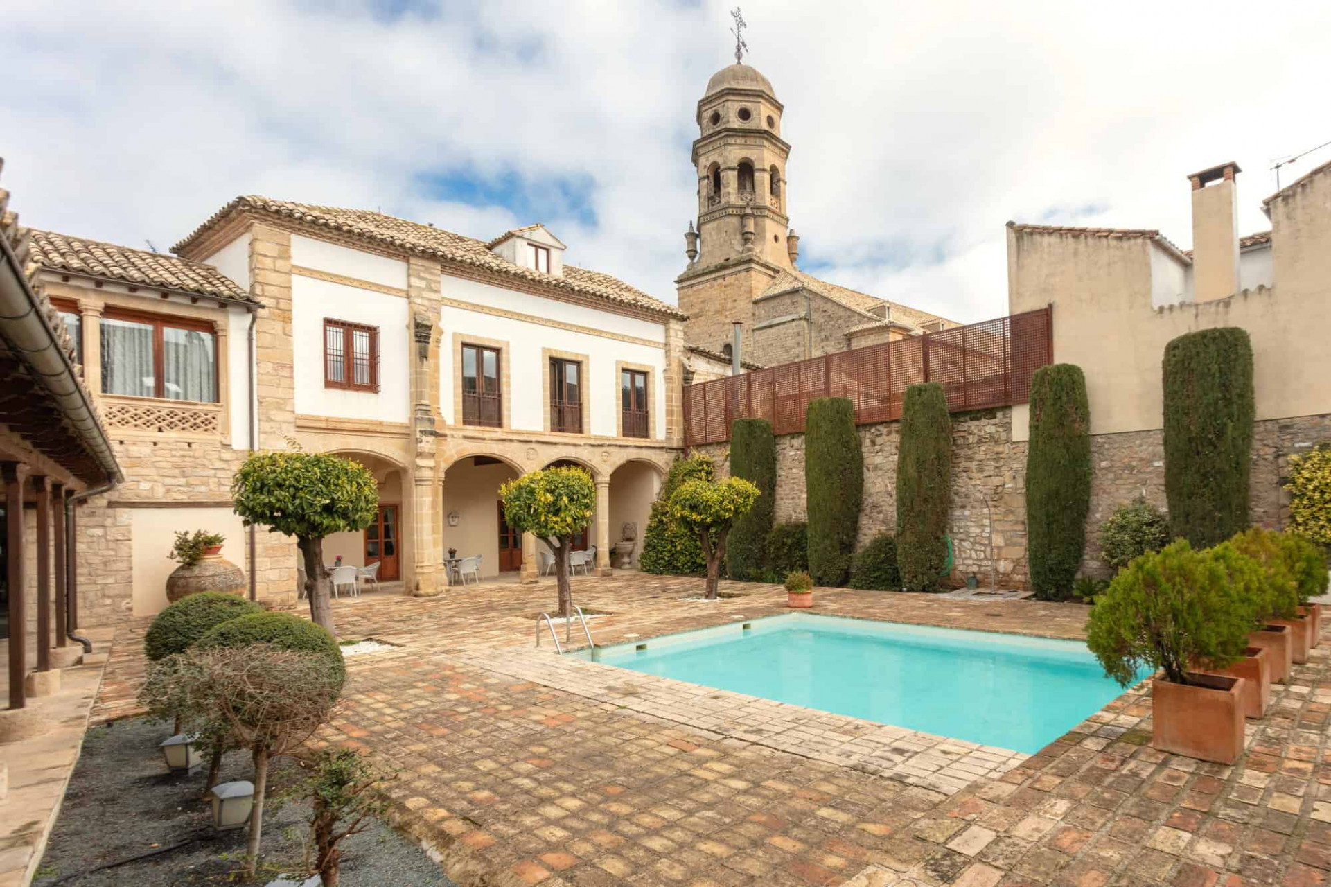 Patio interior con piscina y vistas a la catedral en el hotel Puerta de la Luna en Baeza, Jaén. 